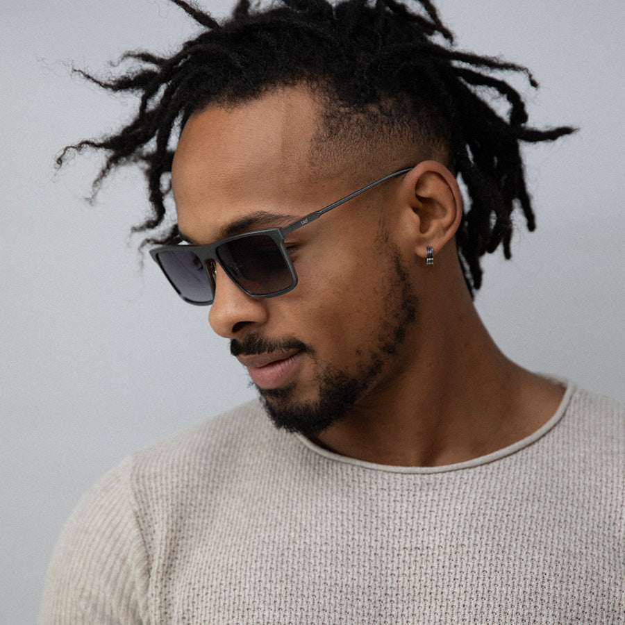 Black man wearing metal rectangle sunglasses looking down